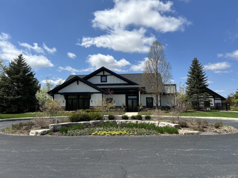 a large, modern clubhouse with a beautifully landscaped front yard