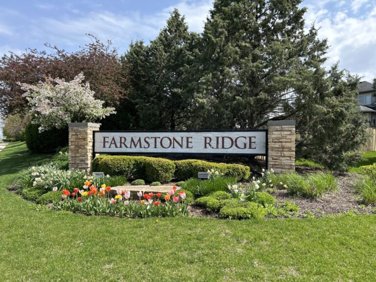 a signage of Farmstone Ridge subdivision surrounded by flowers and tree