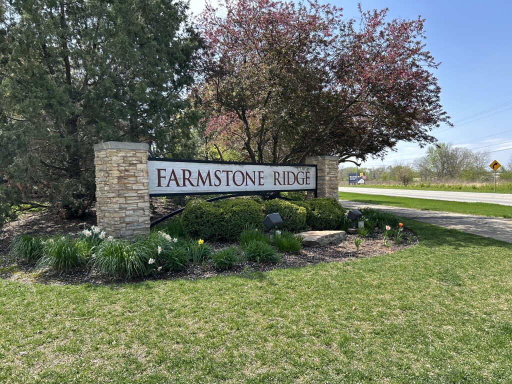 a signage of Farmstone Ridge subdivision surrounded by flowers and tree